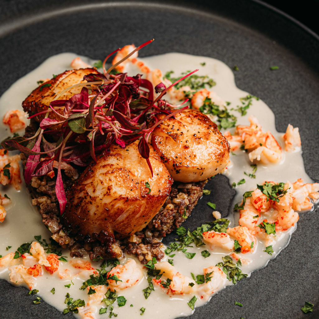 a plate of scallop with crayfish and a cream sauce